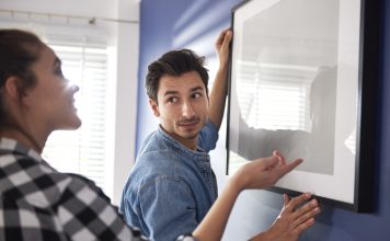 Tijd om de klusjes in de woonkamer aan te pakken! stel dat samen fotolijst ophangt
